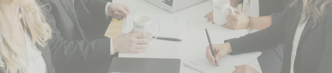 Four lawyers having a meeting holding pens and coffee mugs